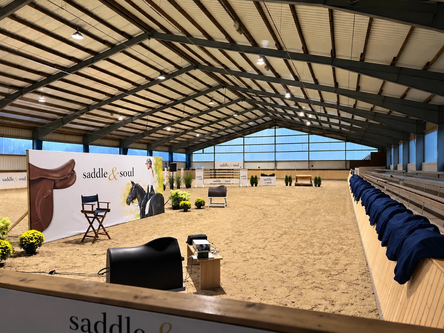 Die Indoorhalle von SADDLE & SOUL: Reitbahn mit Sandboden, Sattelpräsentation, Tribüne an der Längsseite